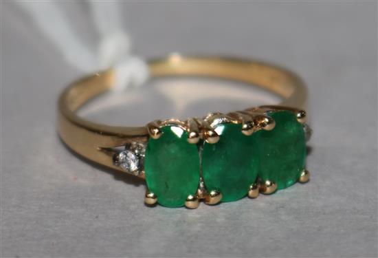 A 14ct gold three stone emerald ring, with diamond set shoulders, size L.